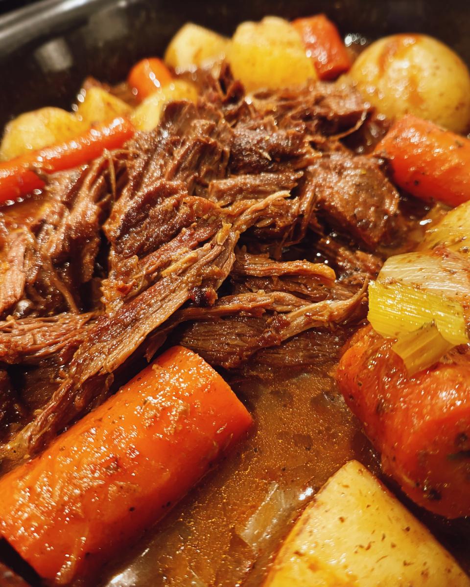 Close-up of tender, shredded pot roast with carrots and potatoes, a perfect example of slow cooker recipes for Sunday comfort.