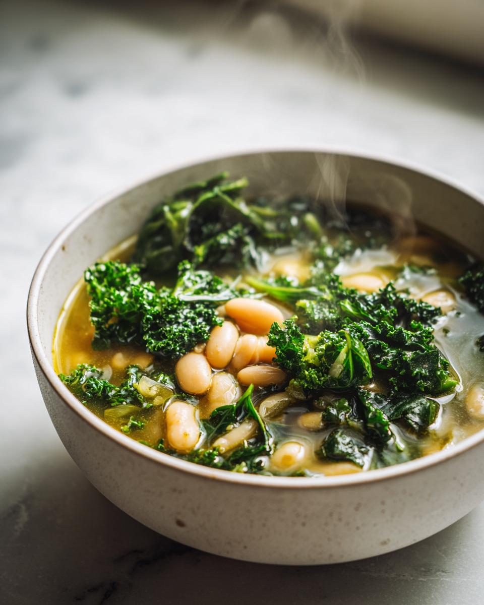 A steaming bowl of white bean kale soup, showcasing tender white beans and vibrant kale in a flavorful broth.